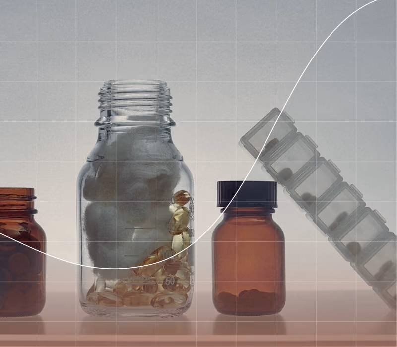 Various medicine bottles and a weekly pill organizer with capsules and cotton inside a jar.