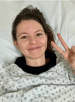 Photo of Ellen Rudolph, WellTheory’s founder, smiling and holding up a peace sign while in autoimmune treatment.