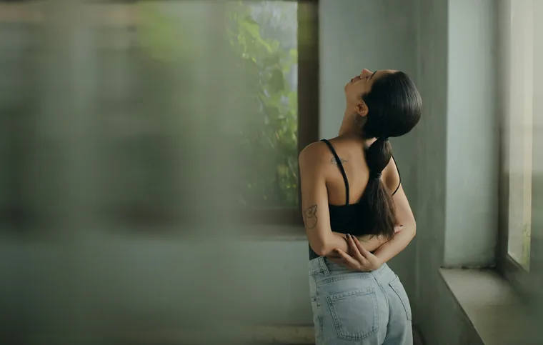 A woman stretching her back beside a window