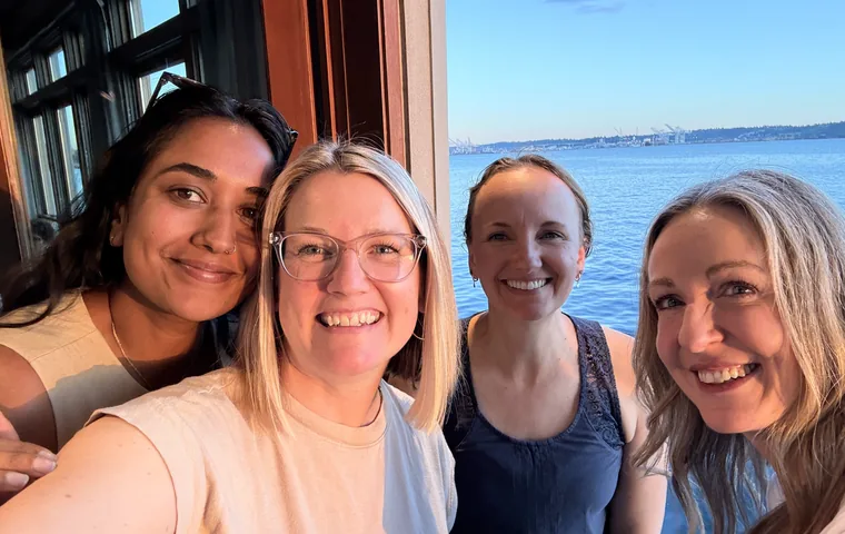 Four WellTheory teammates taking a selfie by the water
