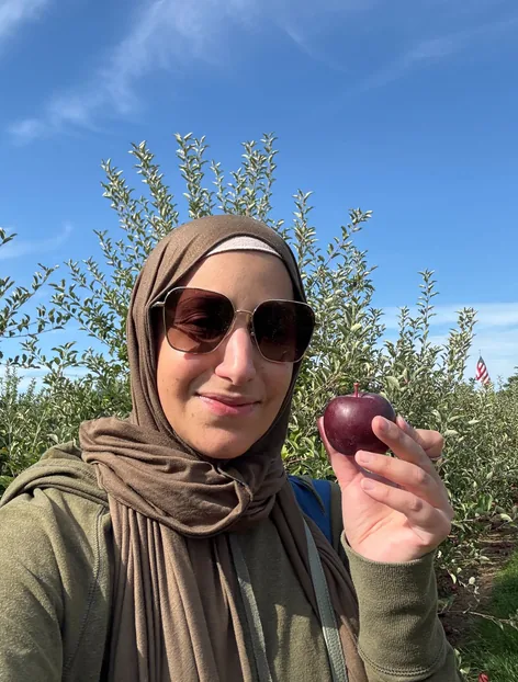 A WellTheory teammate holding an apple in an orchard