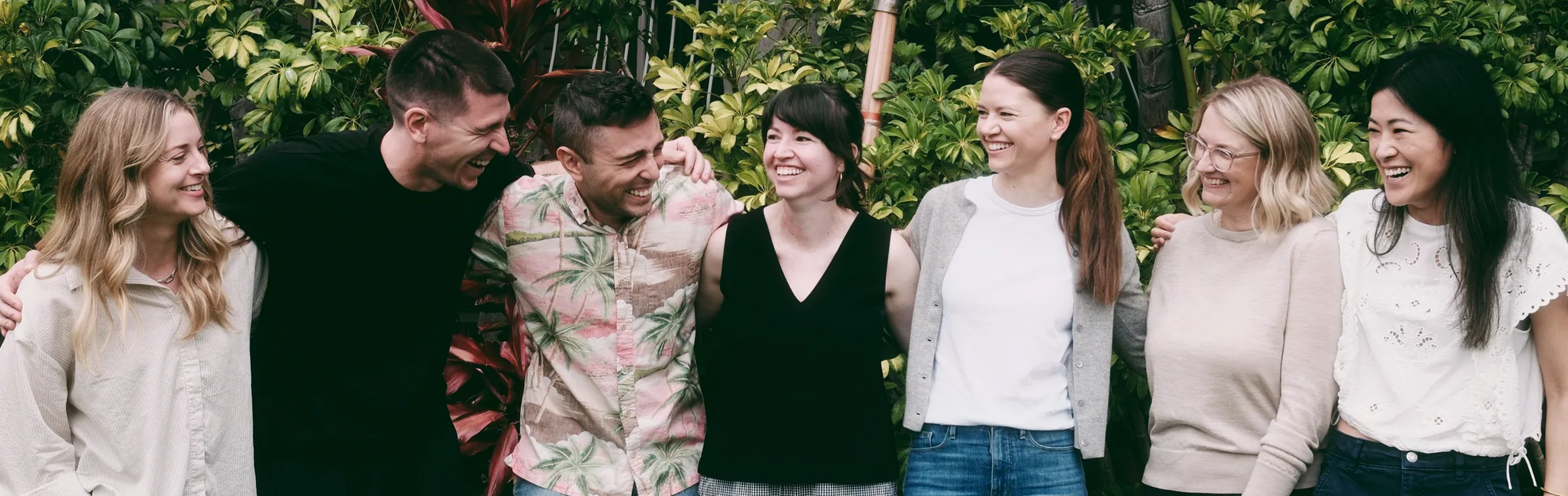 WellTheory's leadership team standing together in front of tropical plants