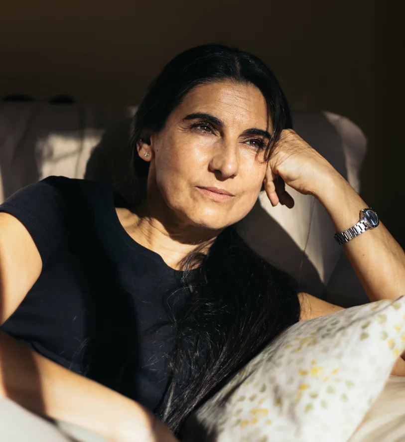 Woman resting her head on her hand on a sunlit couch