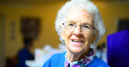 Stara gospa s širokim nasmehom kaže zobne vsadke