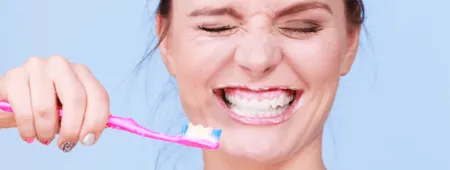 Mlada ženska med ščetkanjem zob in odstranjevanjem kariesa