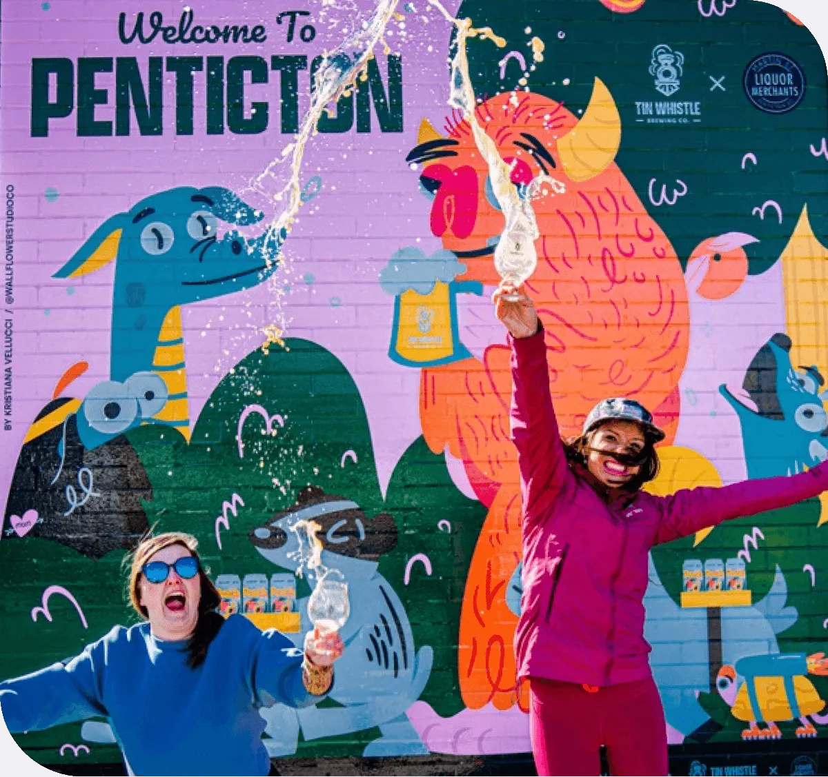 two wome jumping with beer in front of a mural