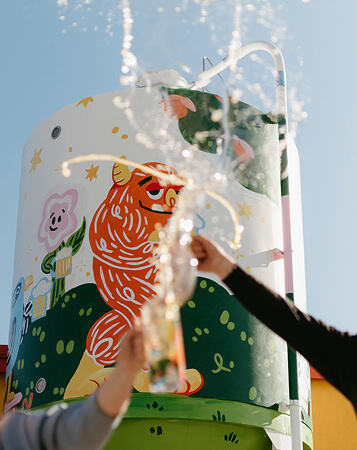 A photo of a mural with two hands cheersing beer as it splashes in front of it