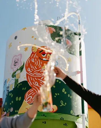 A photo of a mural with two hands cheersing beer as it splashes in front of it
