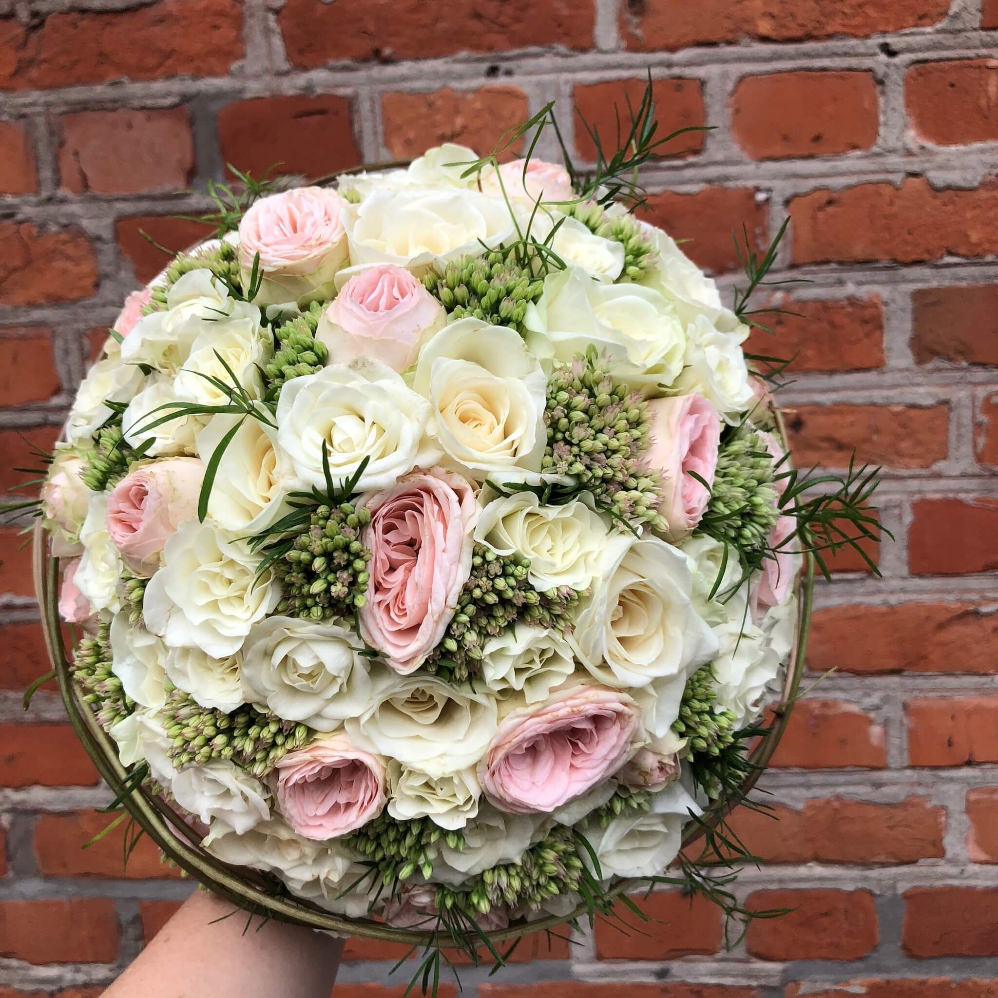 Een bruidsboeket met witte, roze en groene accenten.