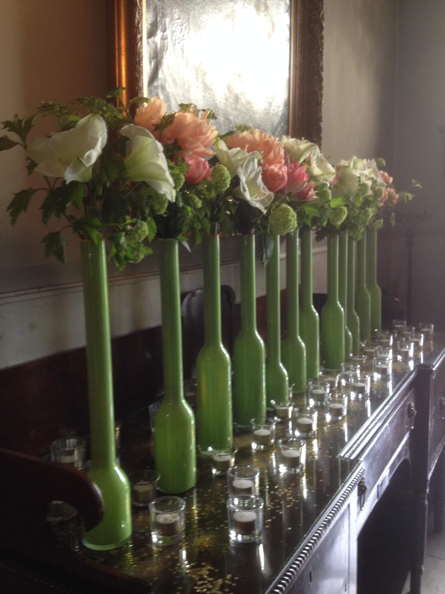 Lijn van lange groene vazen met bloemen.