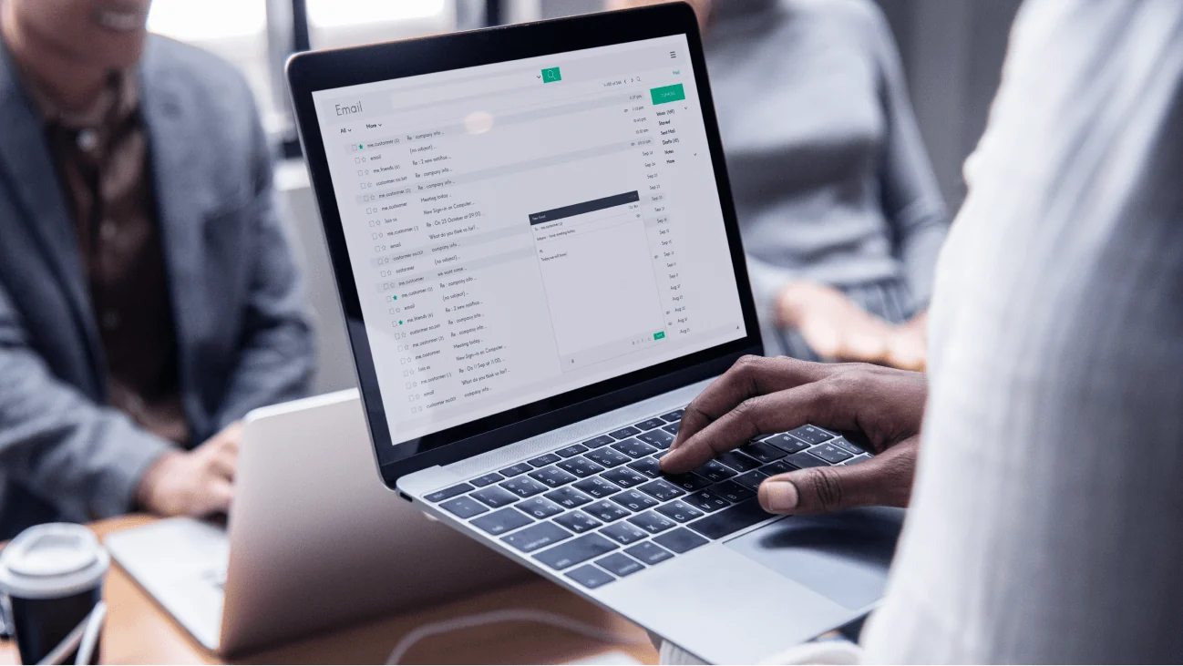 A person using a laptop to manage email security settings in a collaborative office environment.