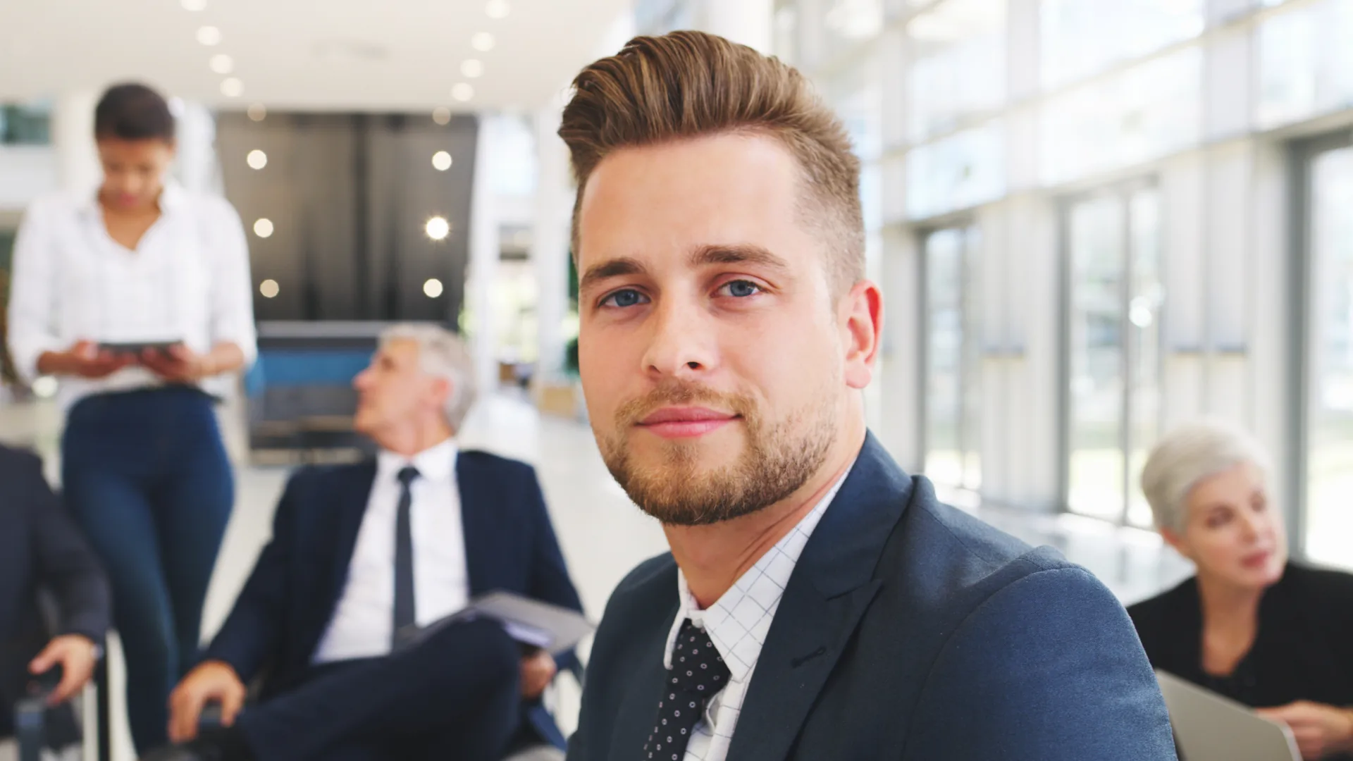 Professional man in a suit in a modern office setting, discussing SaaS security solutions with colleagues.