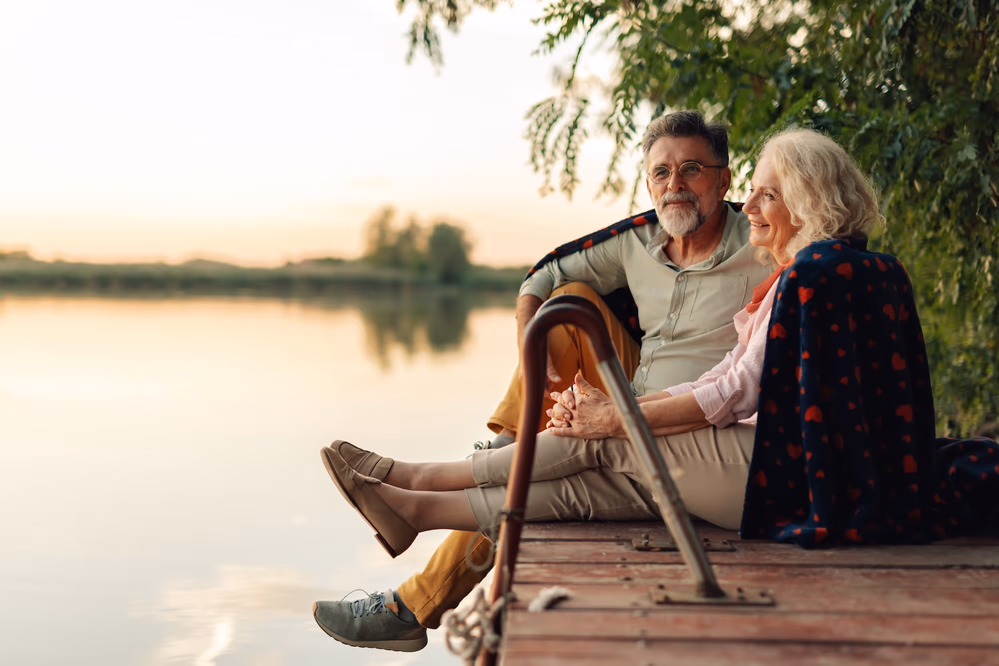 A couple sitting on a dock near a lake
