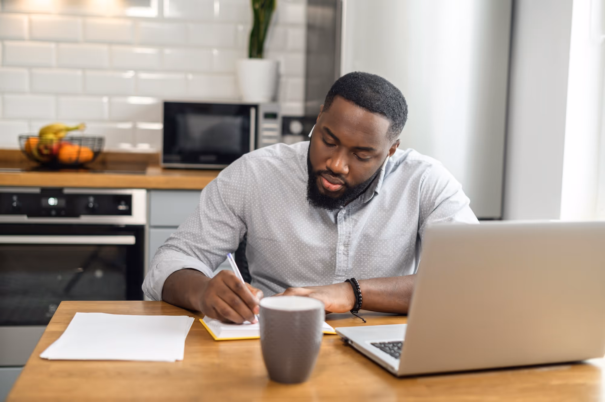 Hard-working man sitting at a table studying, and making notes