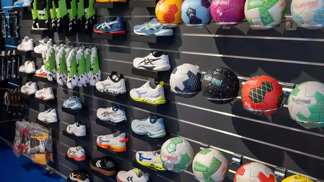 Wand mit unterschiedlichen Sport Schuhen und bunten Hummel-Handbällen in einem Sportgeschäft.