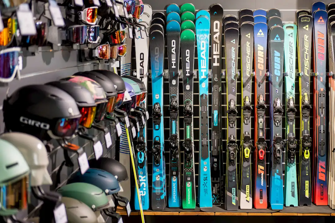 Reihe von Skiern und Helmen in einem Sportgeschäft mit Ski-Ausrüstung.