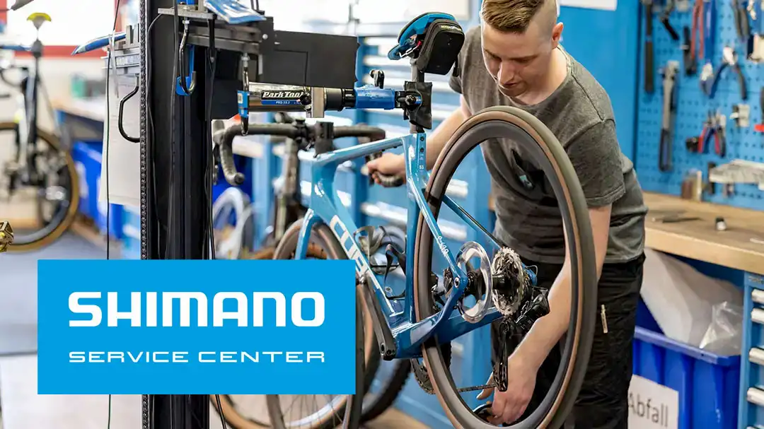 Fahrradmechaniker repariert ein blauer Rennvelo im Shimano Service Center.