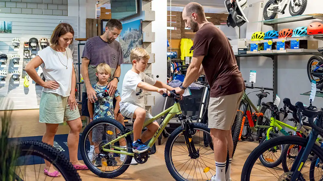 Familie mit zwei Kindern beim Fahrradauswahlgespräch in einem Fahrradgeschäft.