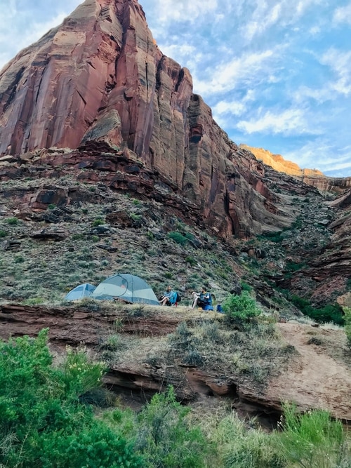 people sitting next to tents in a canyon