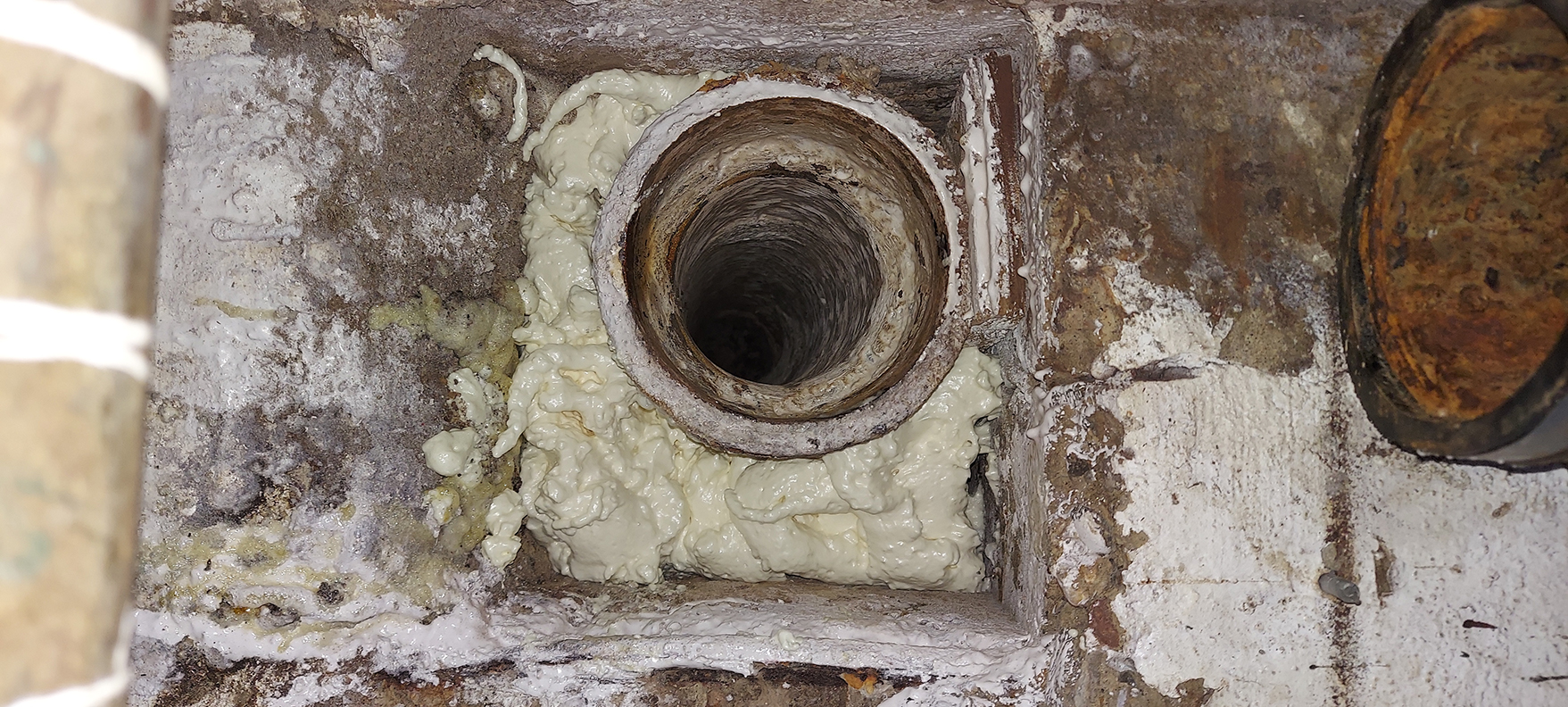 An image of the inside of the inside of a pipe. The pipe has spray sealant around the edges.n