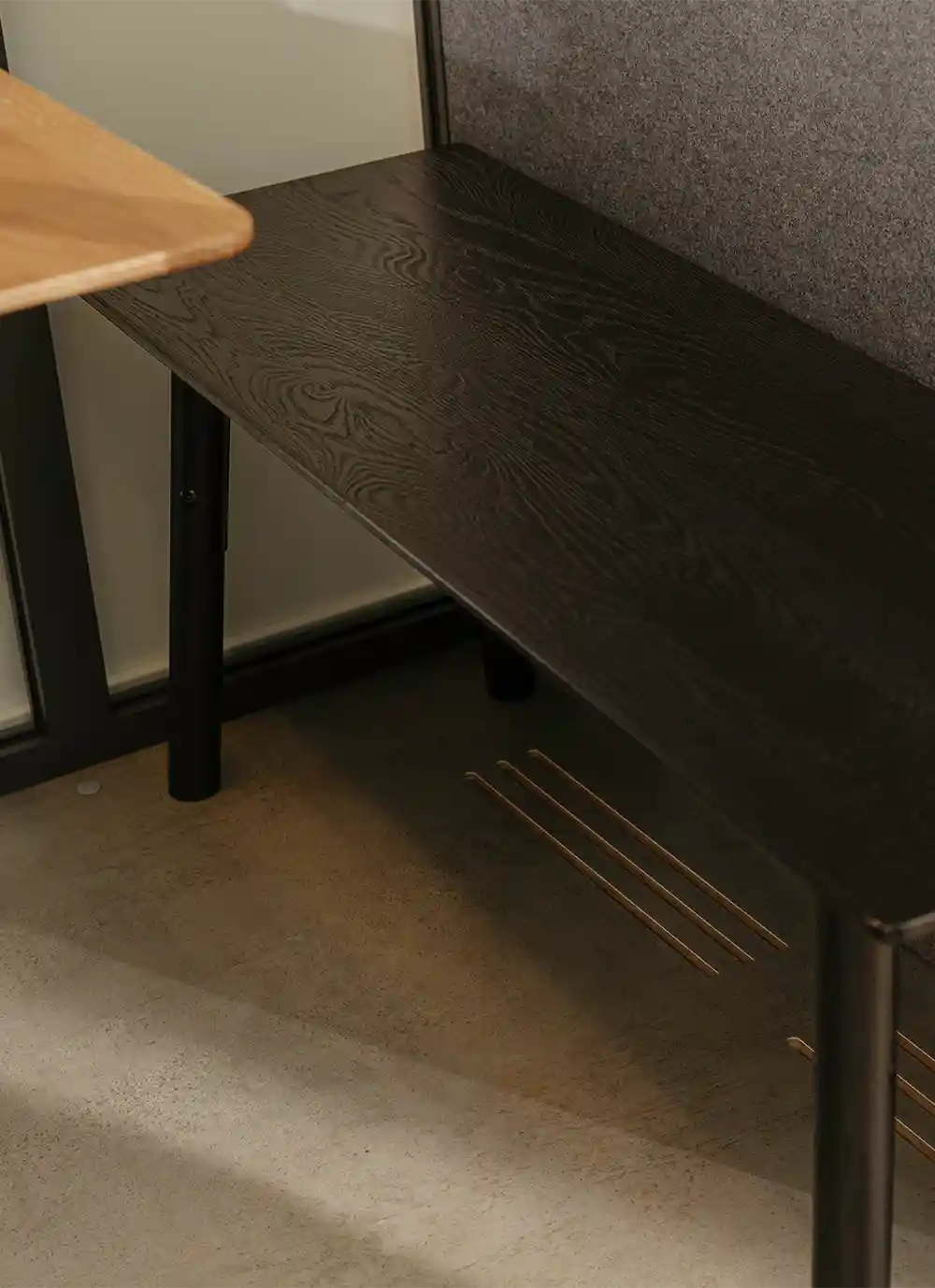 Close-up of black wood grain table surface with black metal legs on concrete floor.