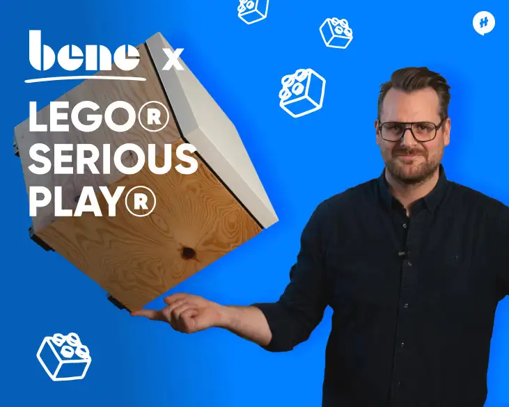 Bene x Lego Serious Play mit David Hillmer vor einer blauen Fläche. Legoillistrationen im Hintergrund