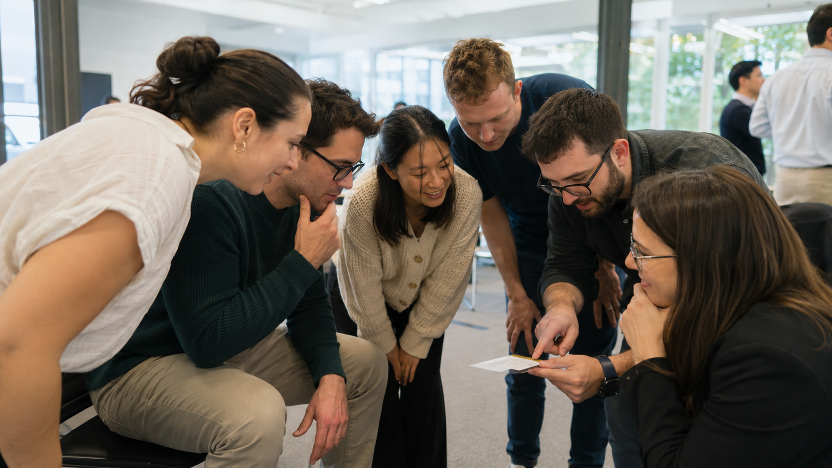 Team members leaning in around a Team Card during the Breakout round activity