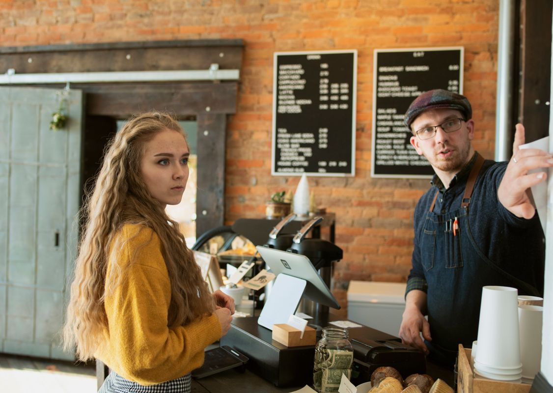 truDigital digital signage menu board above a franchise coffee shop counter as staff serves a customer