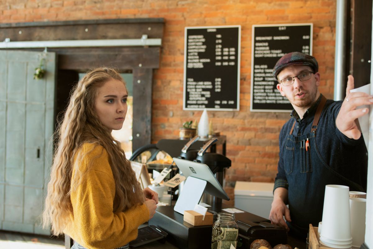 truDigital digital signage menu board above a franchise coffee shop counter as staff serves a customer