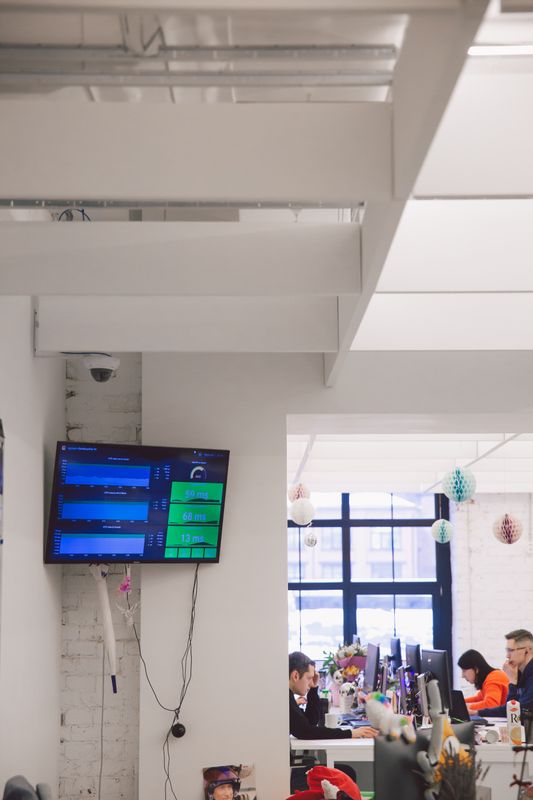 truDigital digital signage screen displaying company data in a modern corporate office with employees working