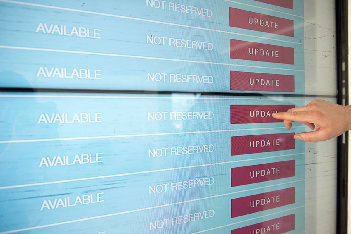 Hand updating content on a large truDigital digital signage touchscreen used for manufacturing plant updates