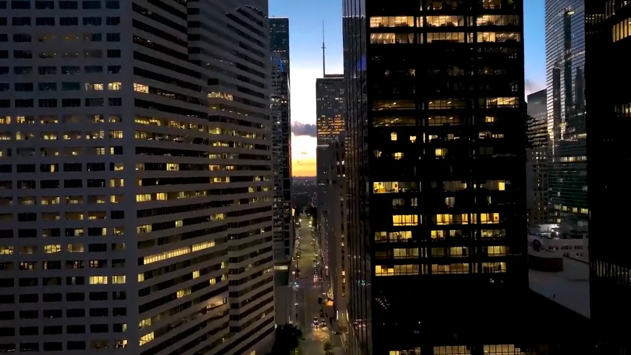 Office towers at dusk with lit windows along a downtown street