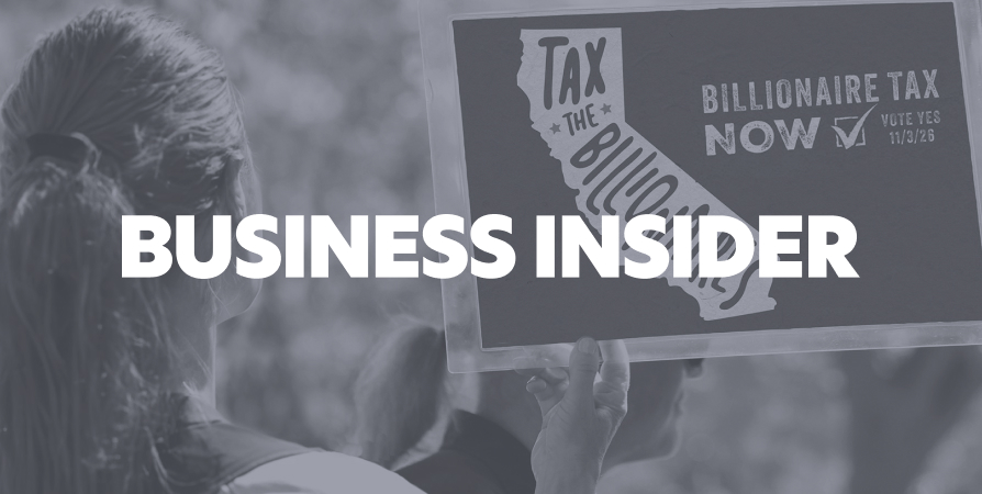 A person holding a Tax The Billionaires sign at a protest