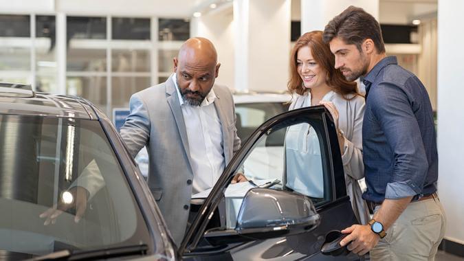 Salesman showing cars feature to a couple