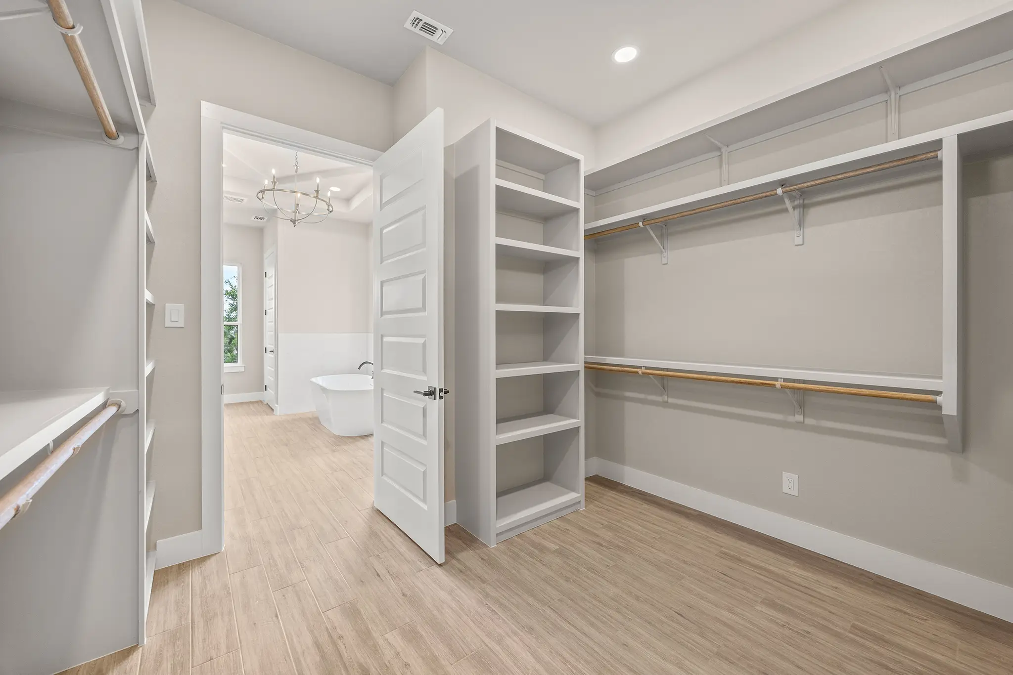 Spacious custom walk-in closet with built-in shelving flowing into a spa-style master bathroom, showcasing KC Custom Homes’ commitment to luxury, functionality, and refined Hill Country living in Cordillera Ranch.