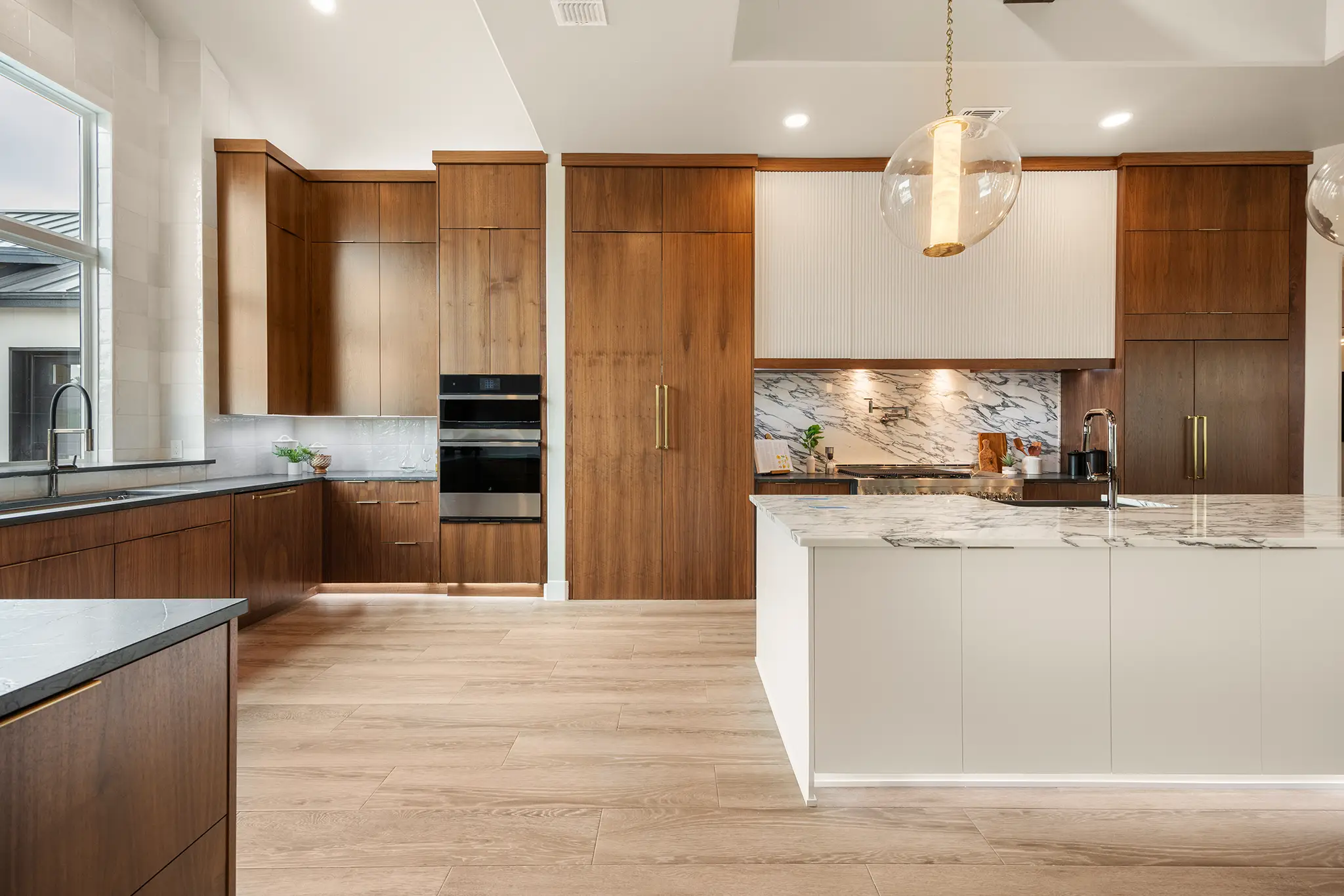 Luxury Hill Country kitchen with natural wood cabinetry, vaulted ceiling beams, and a large marble island designed by KC Custom Homes