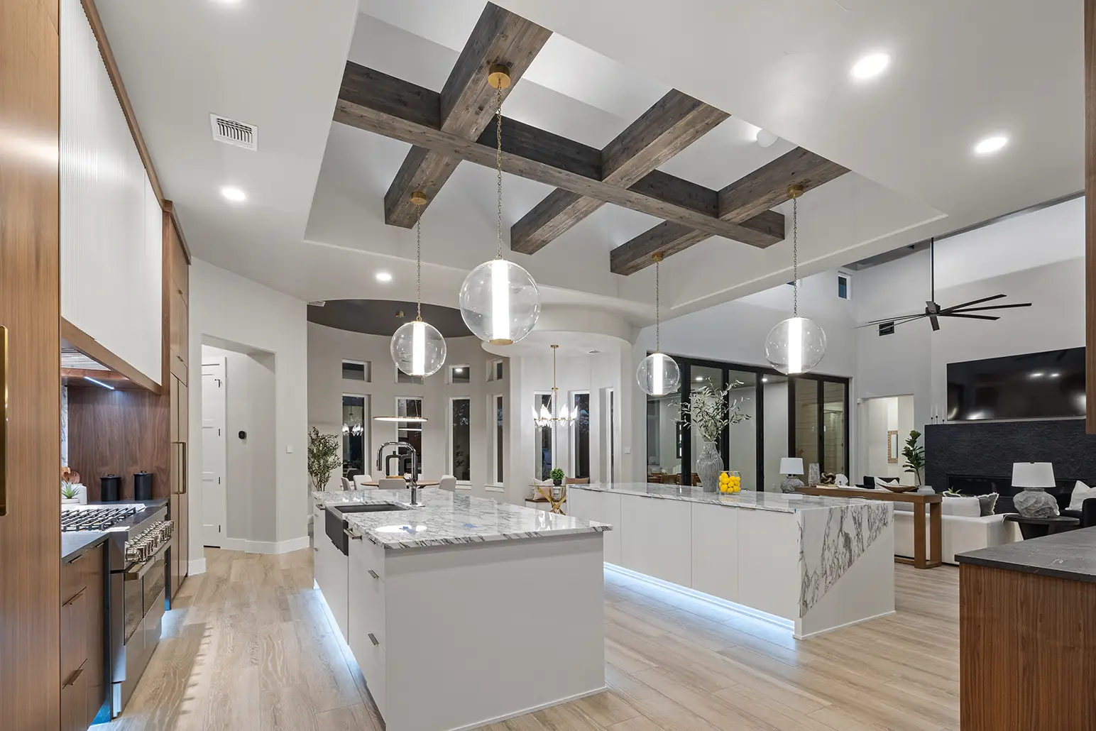 Modern luxury kitchen with double islands, marble countertops, and glass globe pendant lighting in a Hill Country custom home