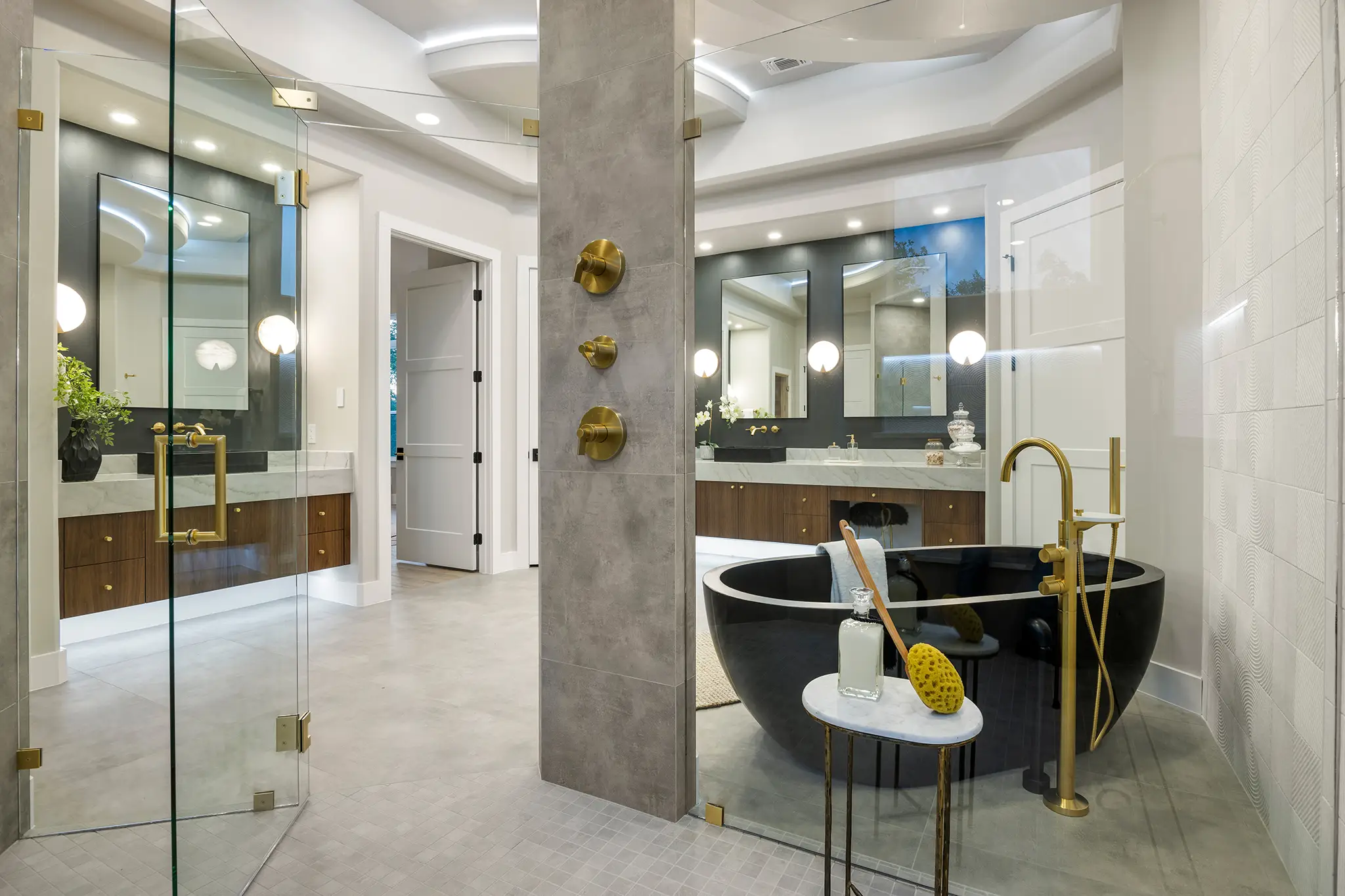 Luxury primary bathroom in a KC Custom Homes residence with a black freestanding tub, gold fixtures, glass shower, and double vanity with marble countertops in New Braunfels Texas.