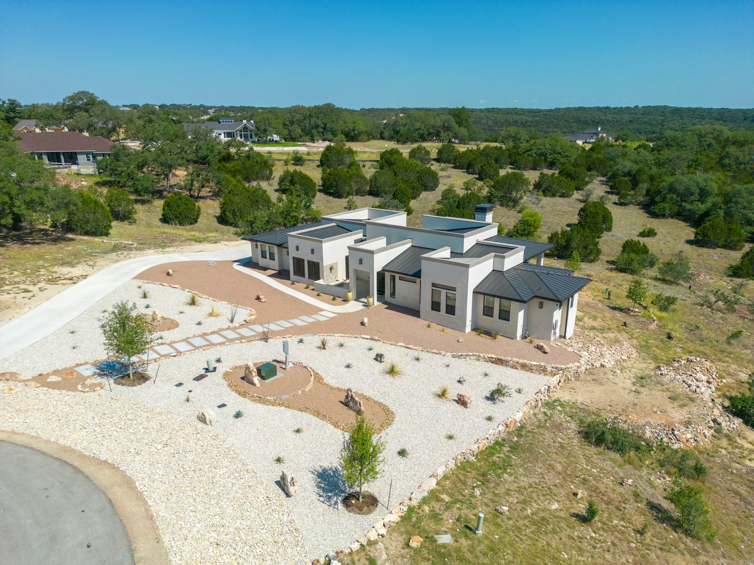 Aerial view of a contemporary flat-roof custom home built on a xeriscaped acreage lot in the Texas Hill Country near New Braunfels.