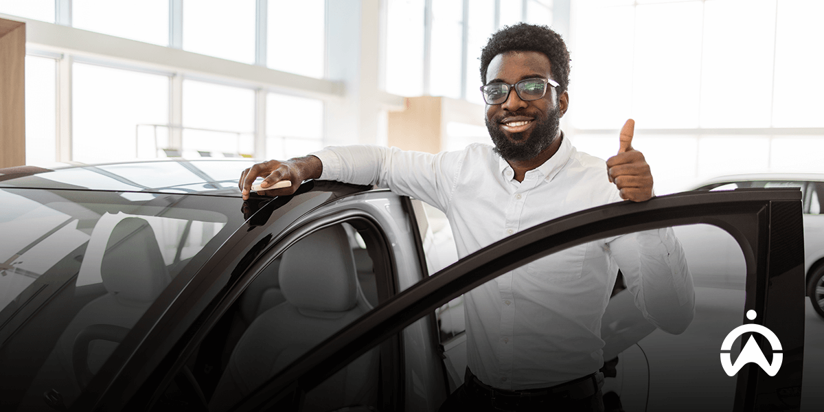 Person holding car keys near a vehicle while giving a thumbs-up gesture.