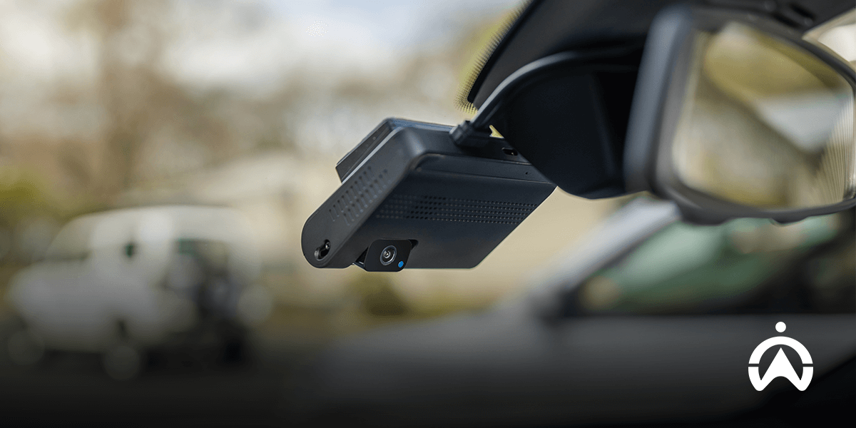 Dashcam attached to a car's windshield with blurred background.