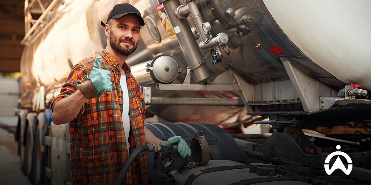 Worker holding fuel nozzle beside tanker, highlighting faulty fuel management system issues.