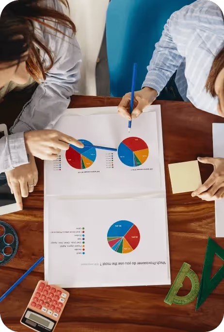 Three people working on a pie chart on a table