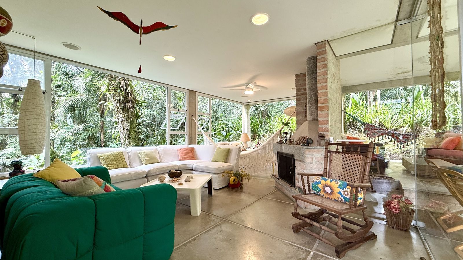 Sala de TV com sofá amplo e vista para o verde – Casa 812