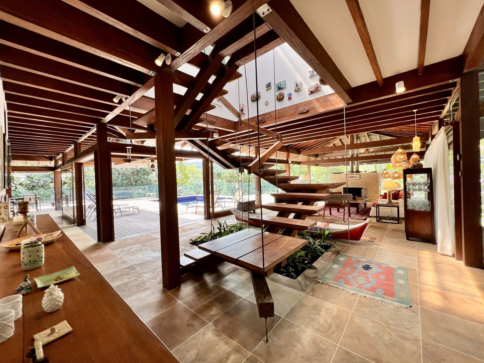 Piscina em deck de madeira cercada por vegetação – Casa 784