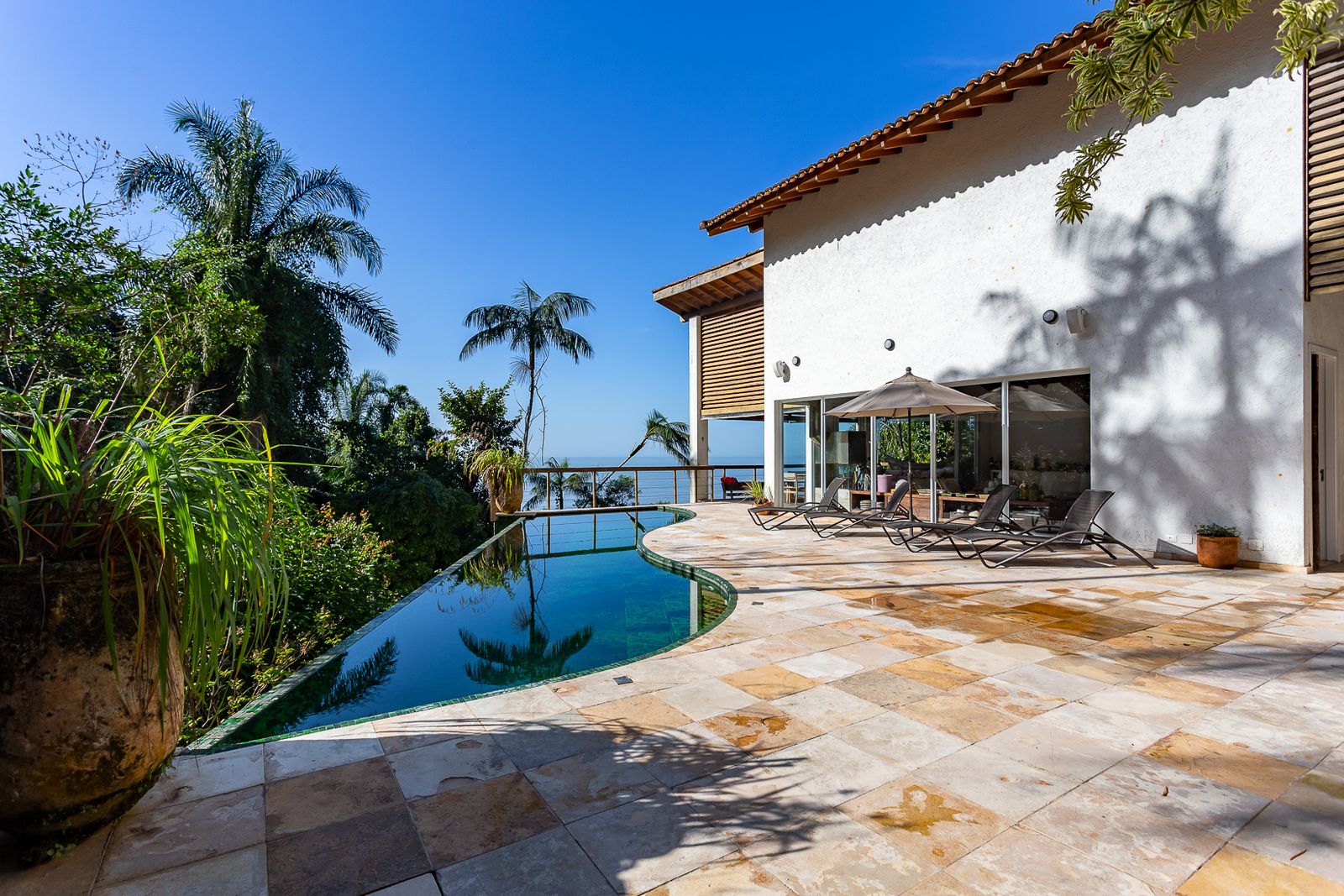Piscina infinita emoldurada por vegetação exuberante – Casa 679