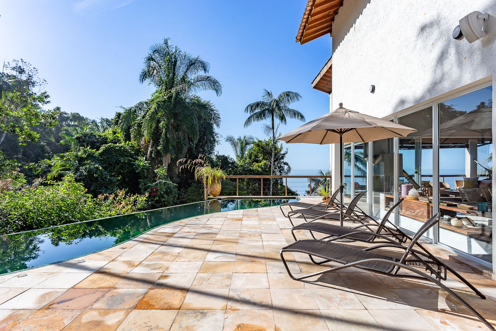 Varanda principal com rede, mesa turquesa e mar – Casa 679