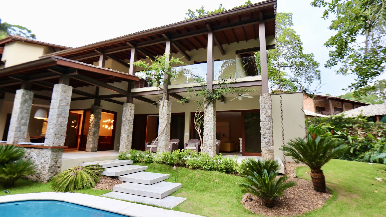 Piscina envolta por vegetação tropical e área verde – Casa 706