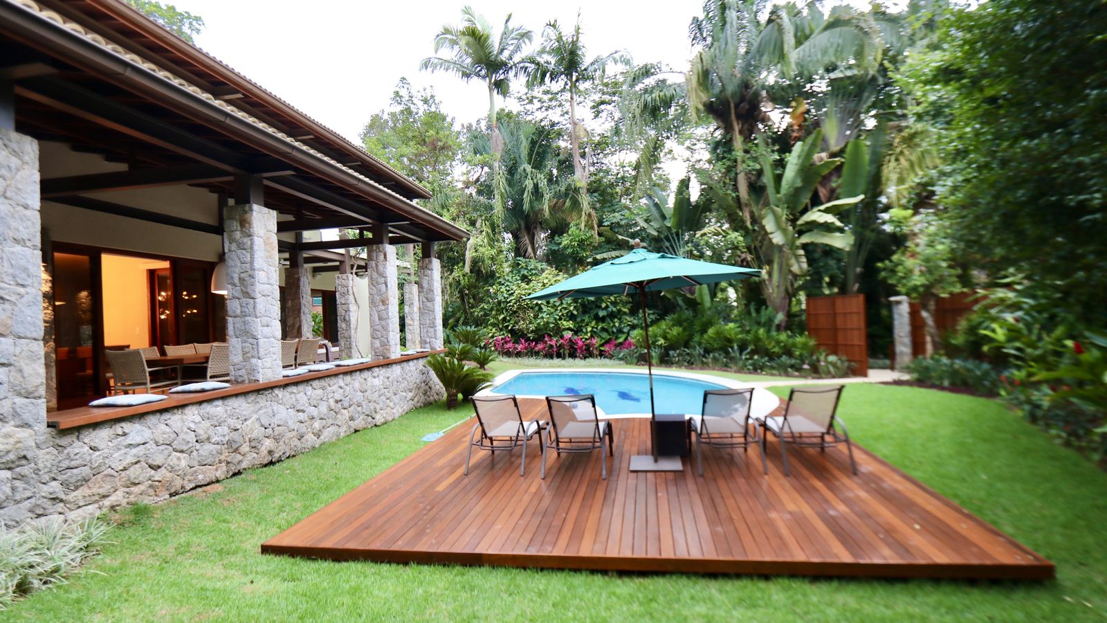 Varanda coberta com pilares de pedra e vista ao jardim – Casa 706