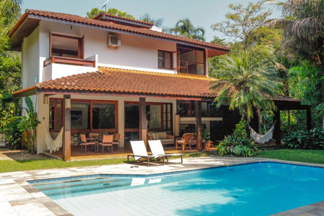 Fachada posterior com piscina e jardim tropical – Casa 702